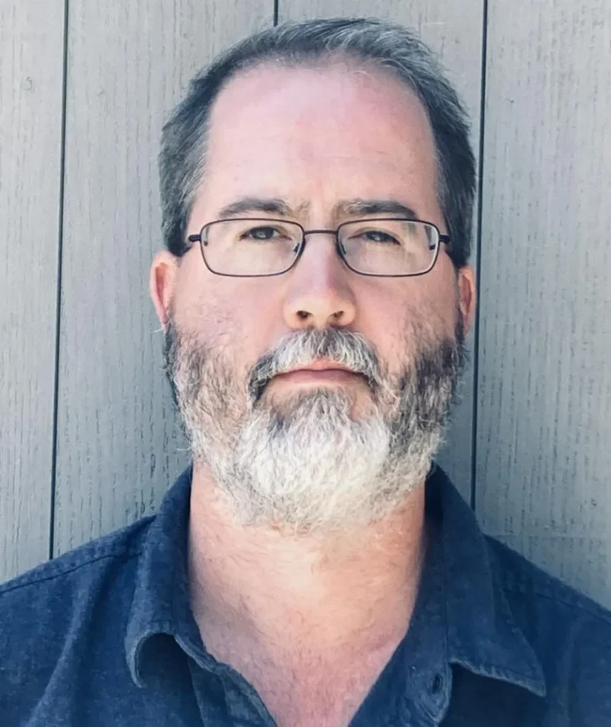A headshot of a bearded man