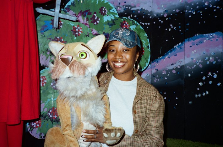 a woman in a hat holding a puppet of a mountain lion