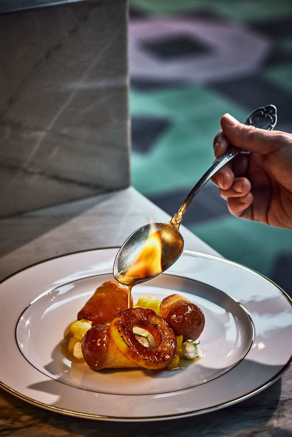 A hand spoons liqueur over a baba au rhum, while it’s on fire, at JouJou.