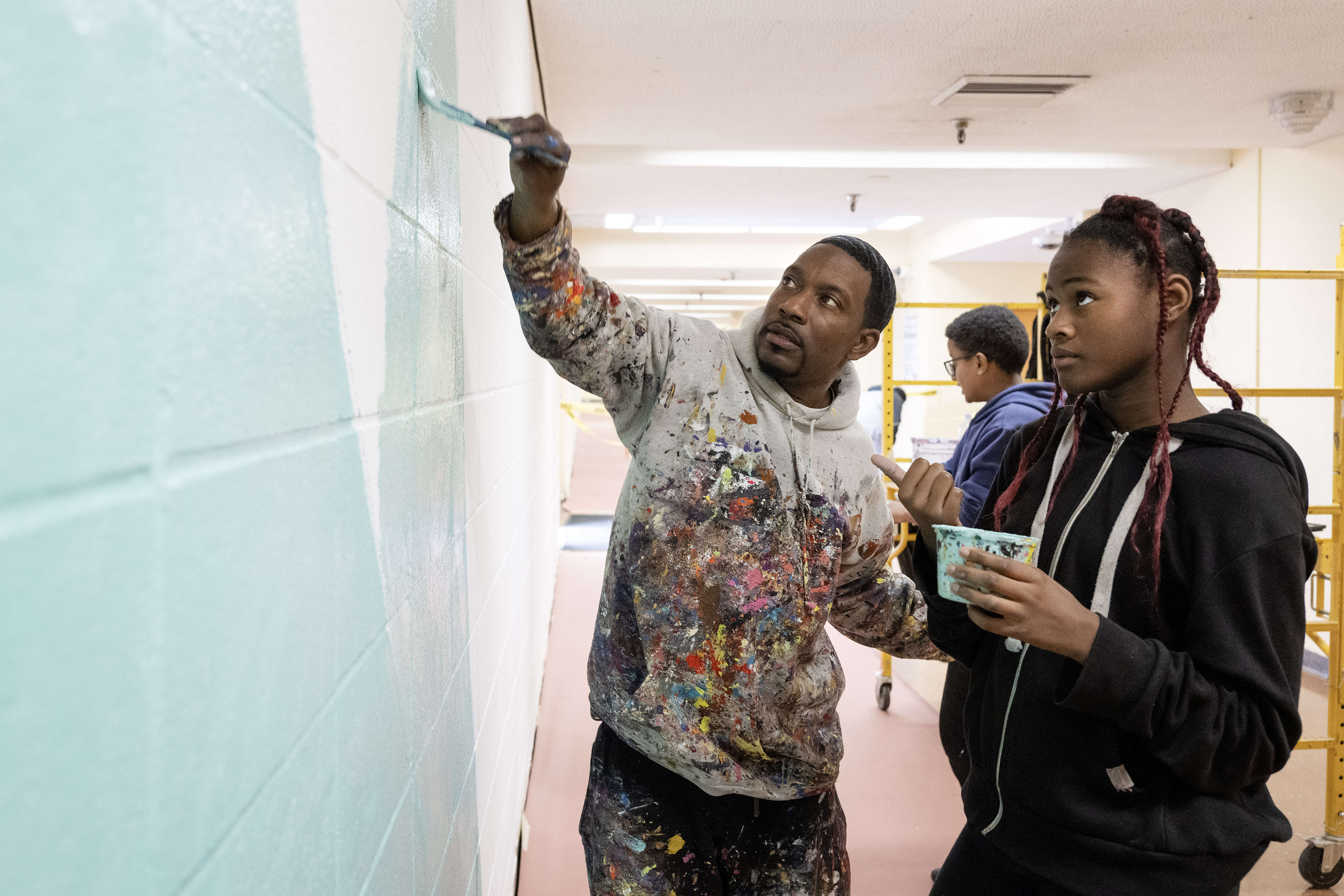 From left, Muralist Mike Norice teaches eleven-year-old Serenity Williams proper...