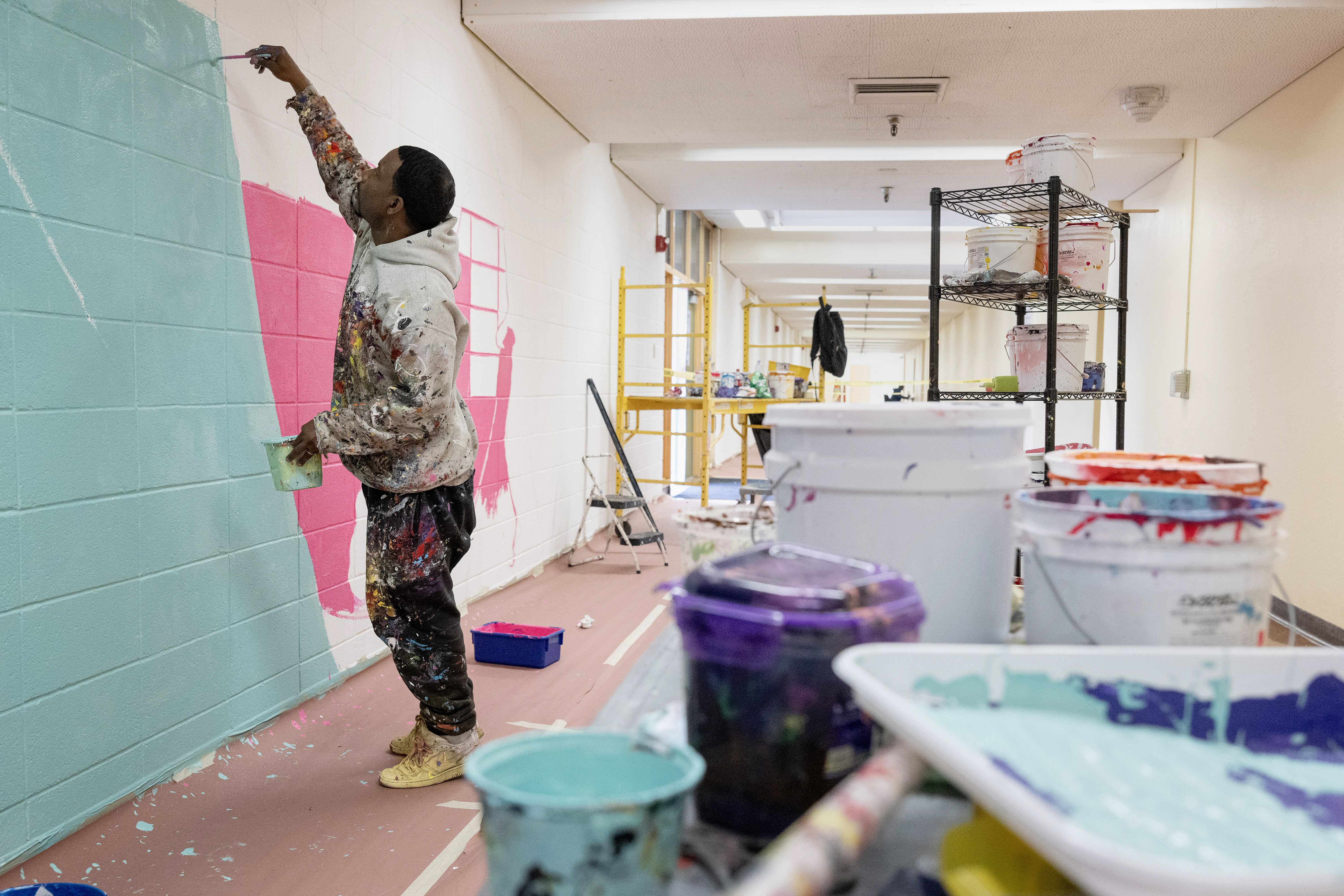 Artist Mike Norice works on a mural at Audubon Middle...