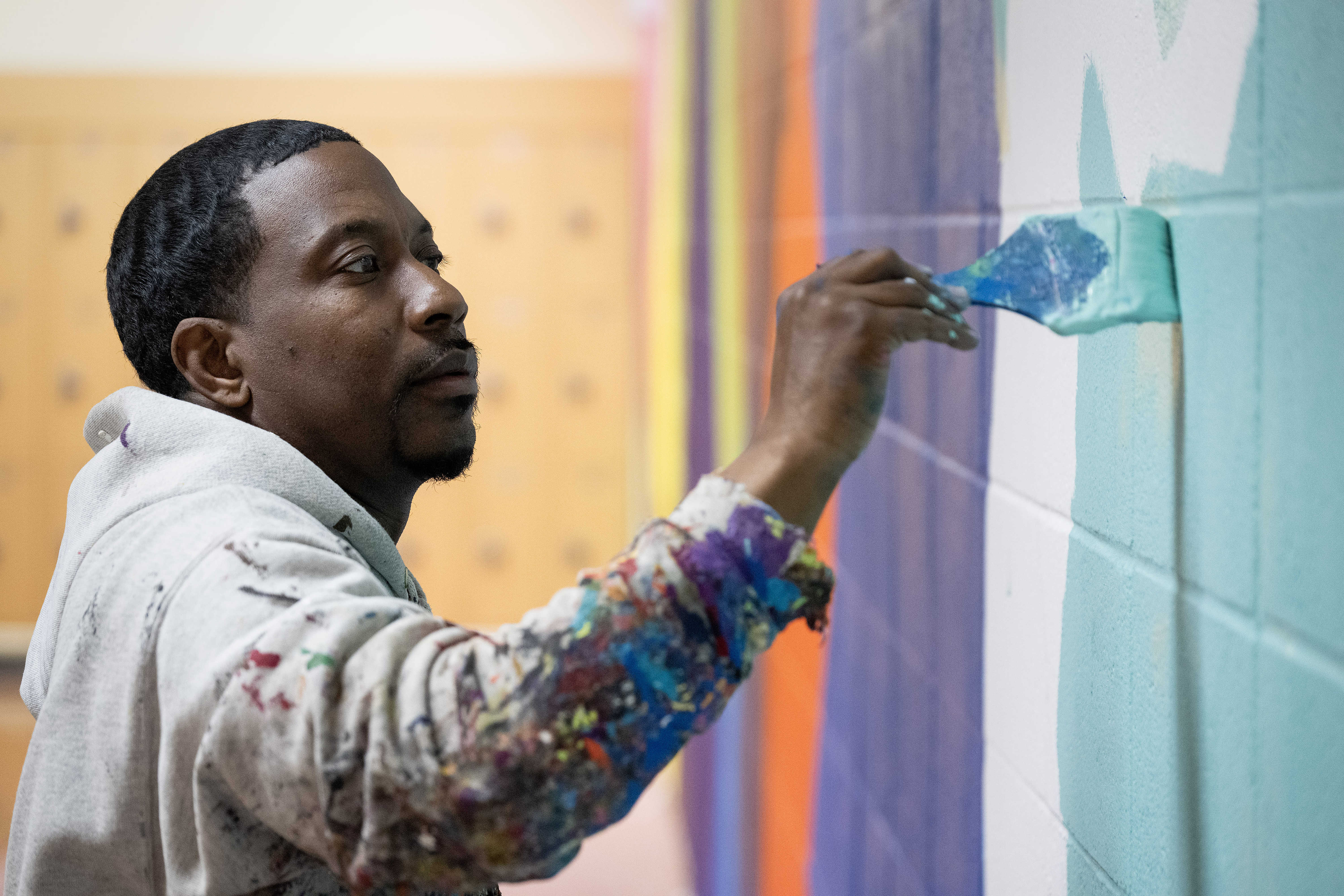 Artist Mike Norice works on a mural at Audubon Middle...