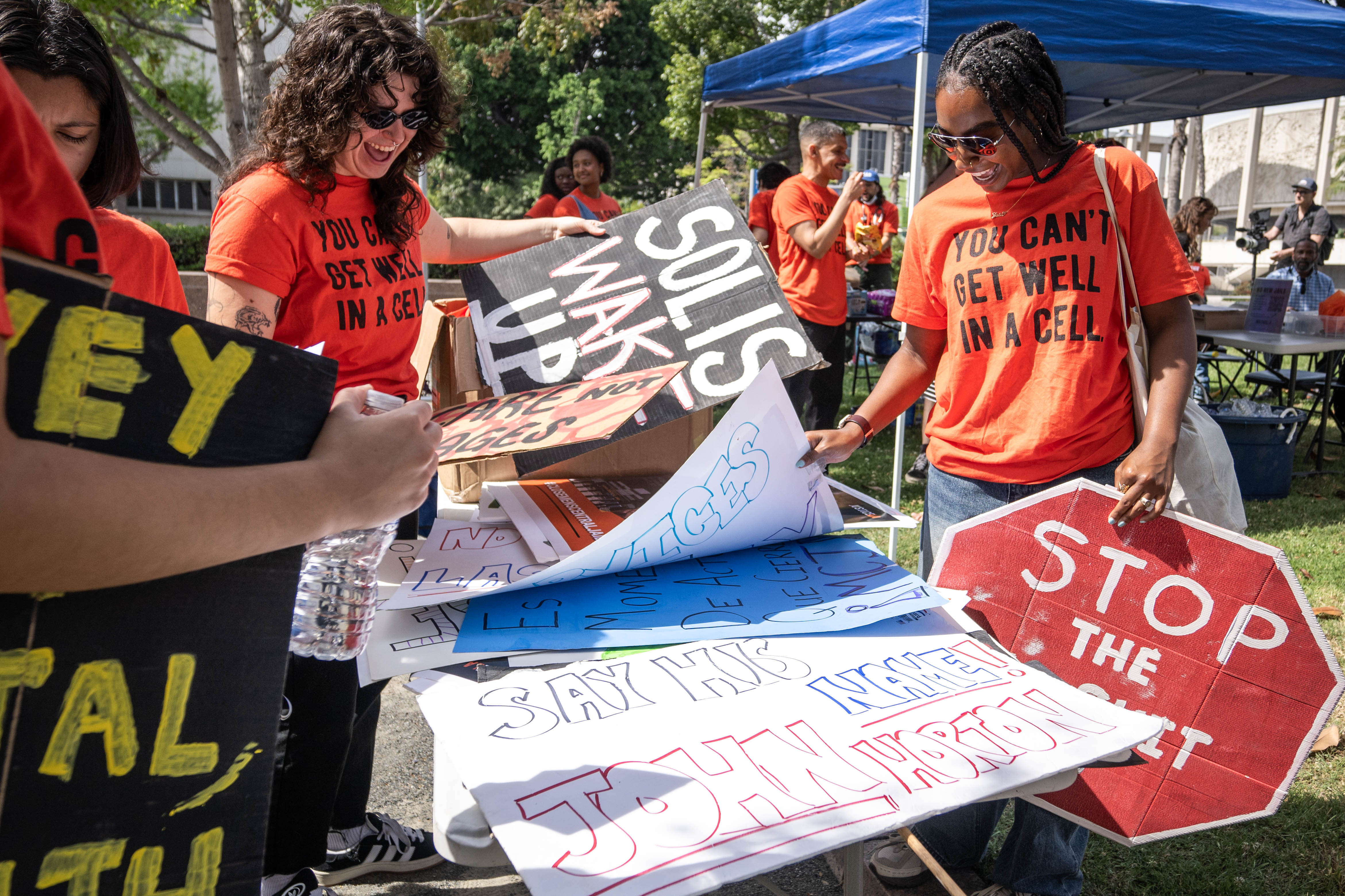 People pick signs during a JusticeLA coalition rally calling for...