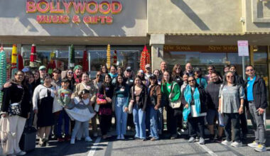 A group of students stand in front of a Bollywood Music and Gifts store in Little India