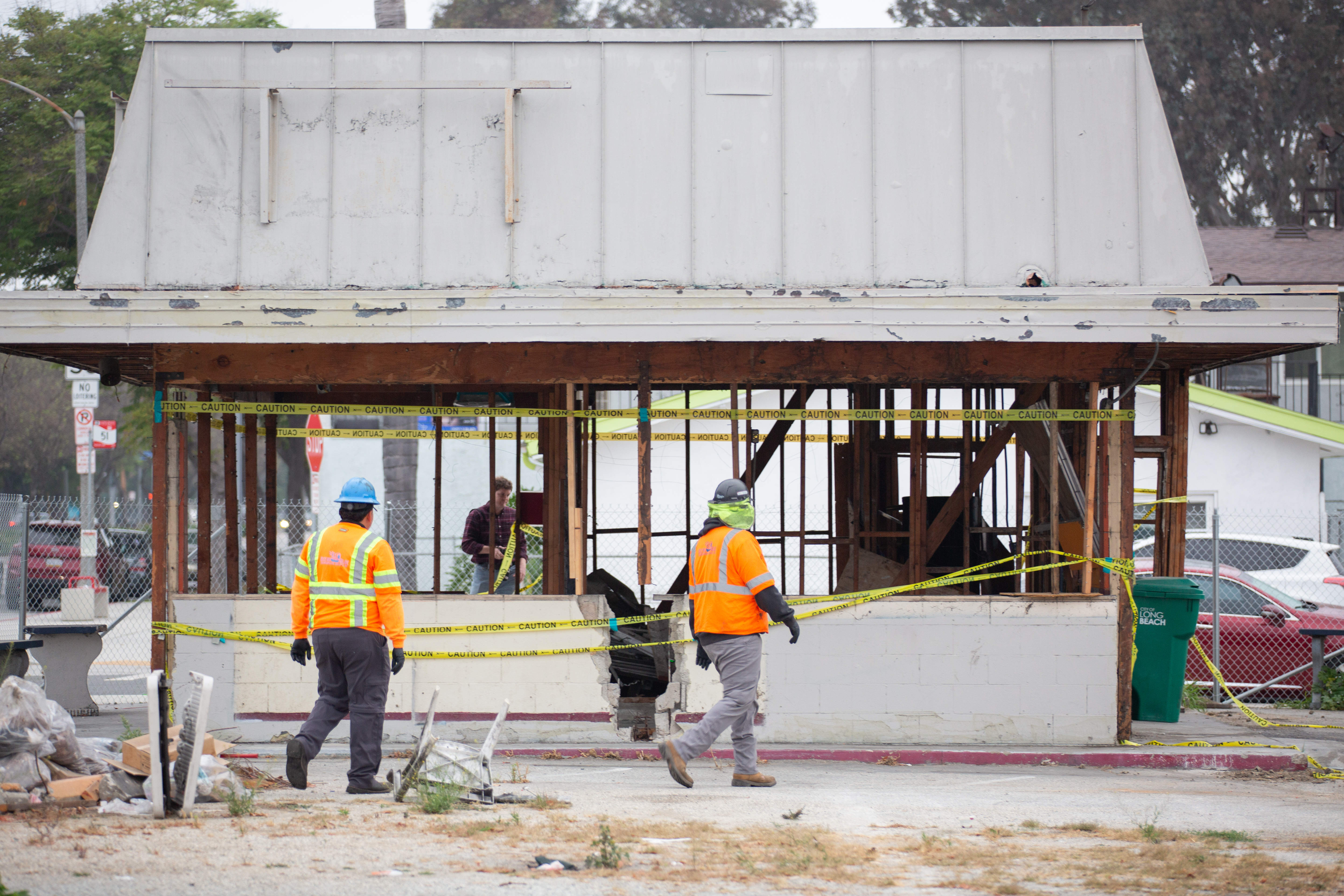 Workers walk past a gutted fast food restaurant as they...