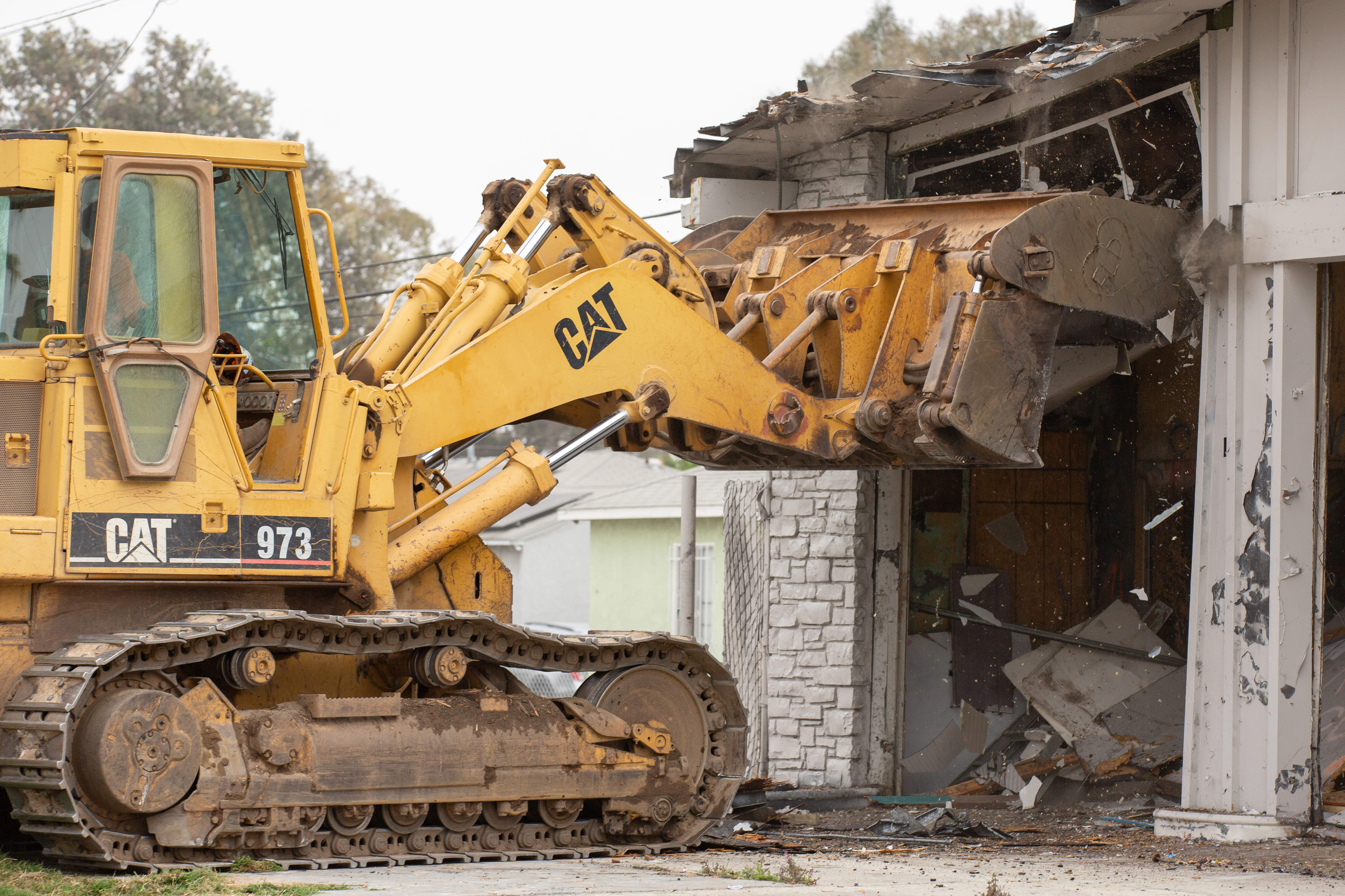 Work crews work to demolish an abandoned fast food restaurant...