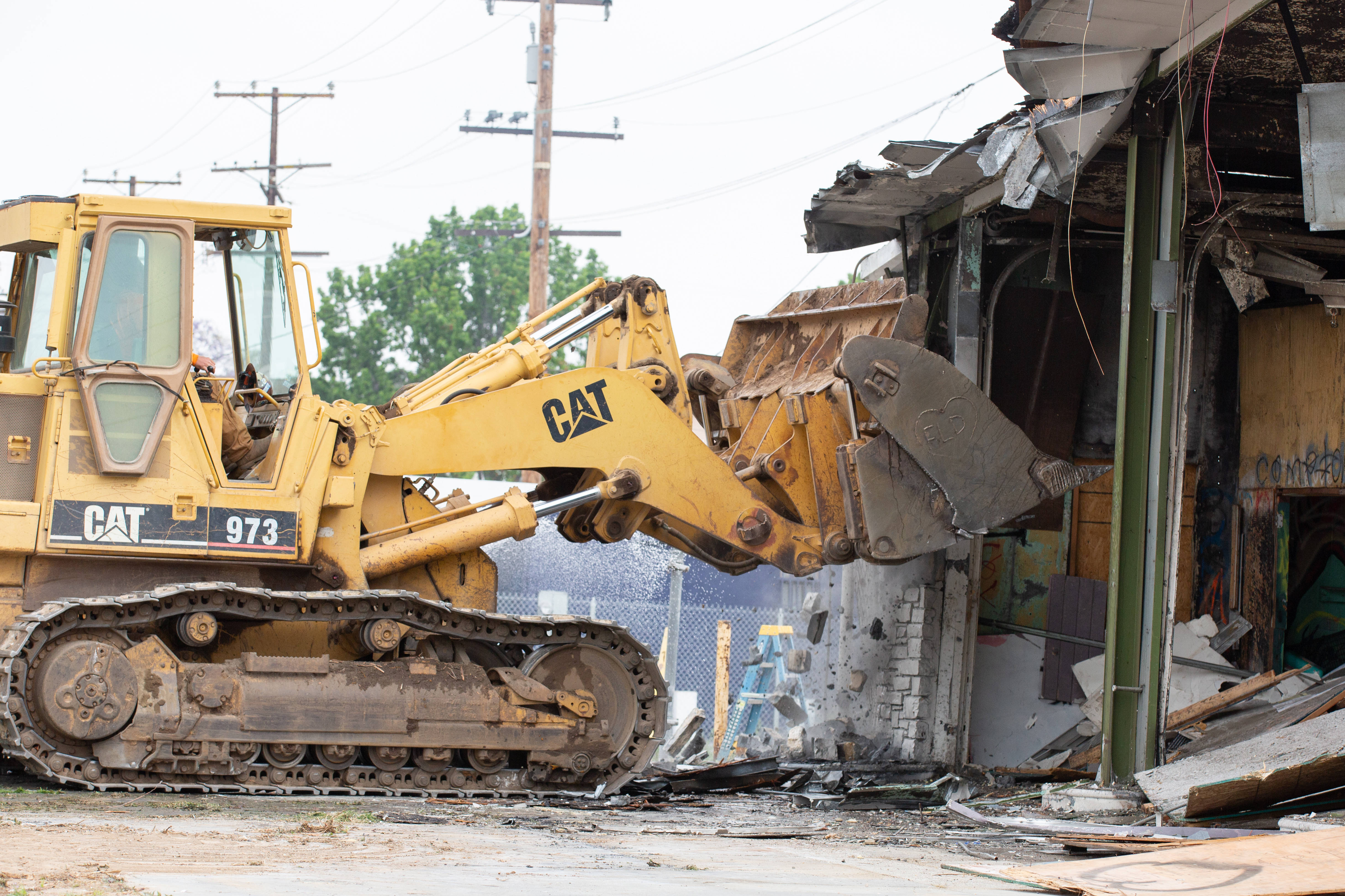 Work crews demolish an abandoned fast food restaurant and gas...