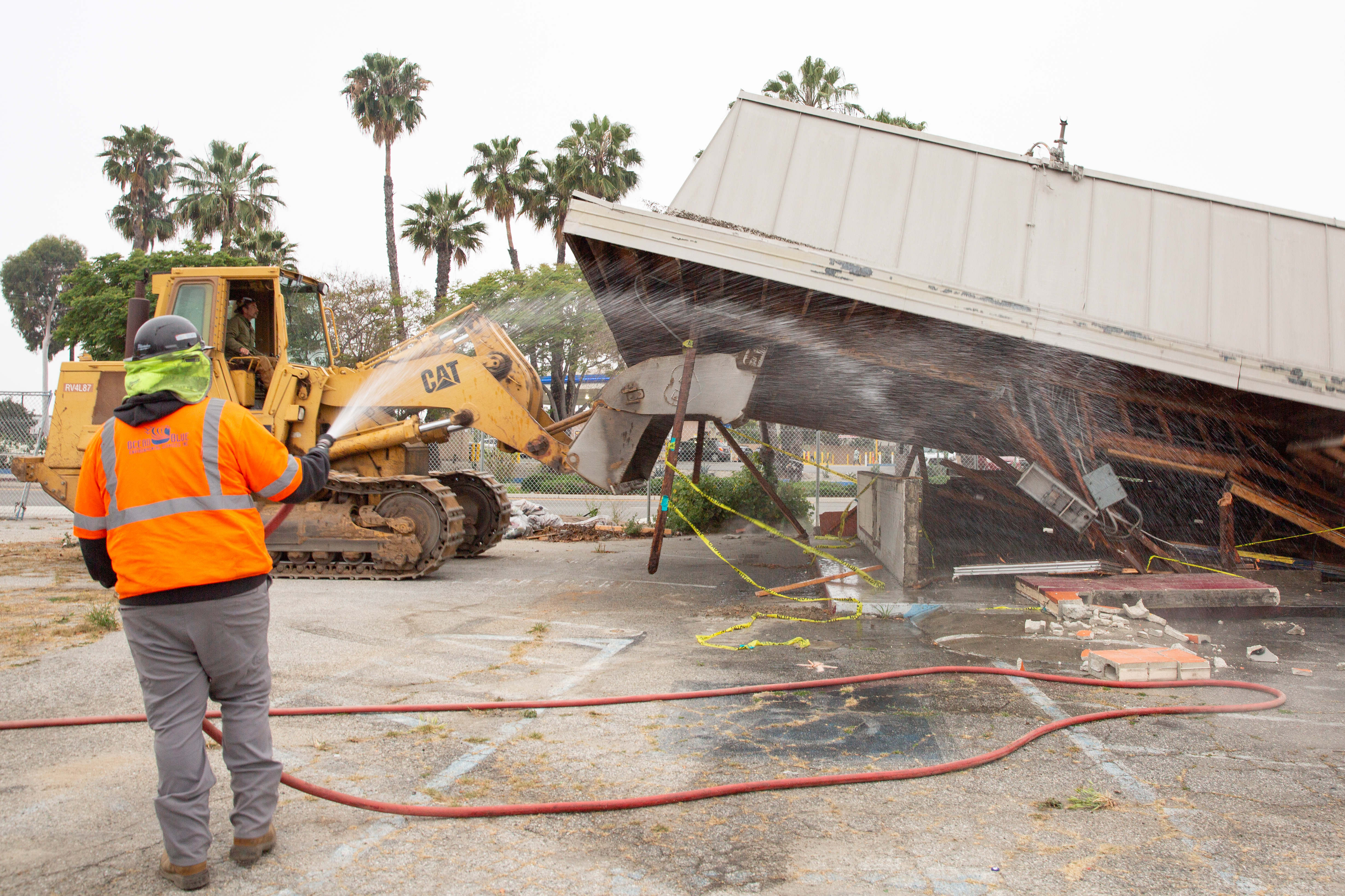 Work crews pull down the roof as they demolish an...