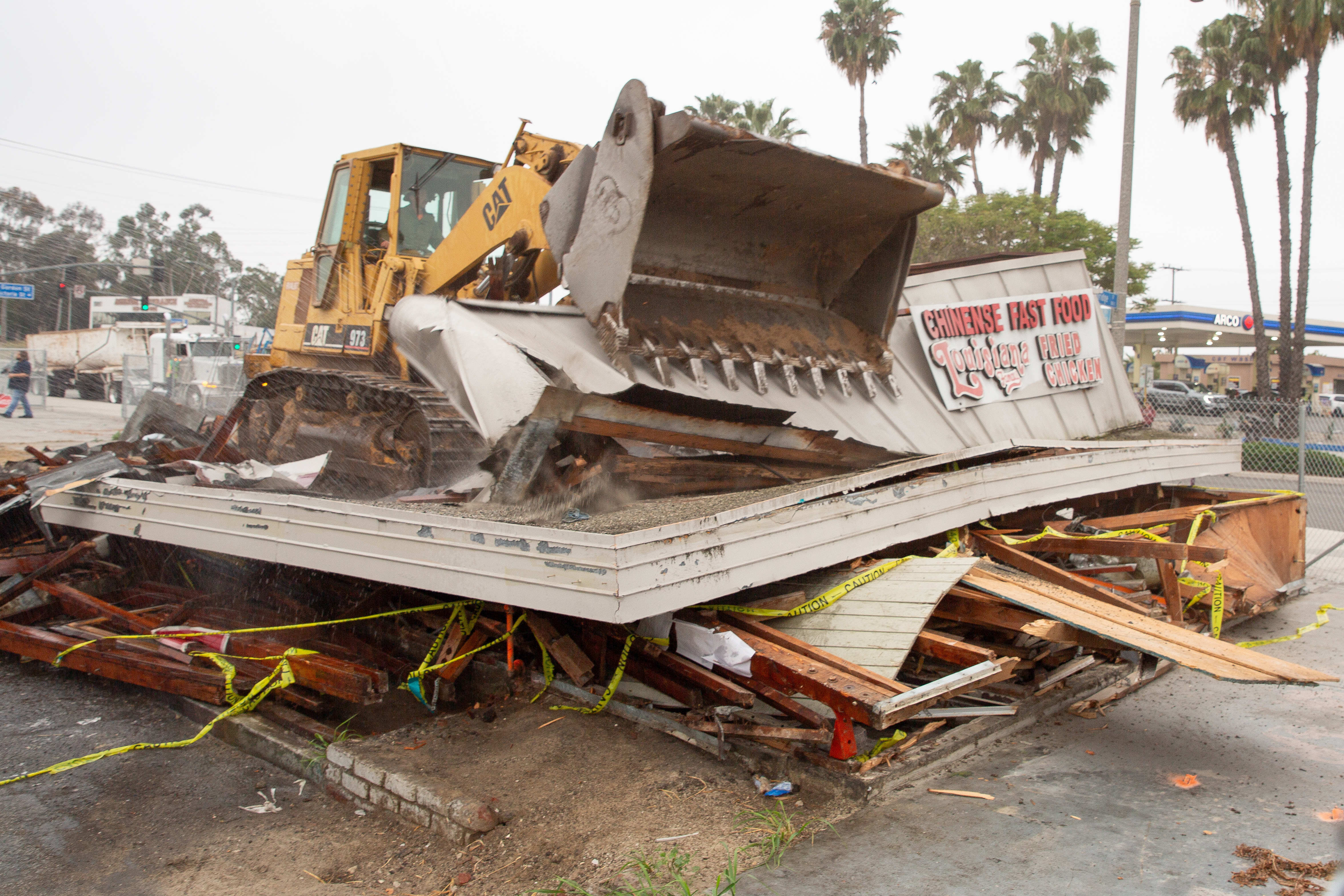 Work crews demolish an abandoned fast food restaurant and gas...