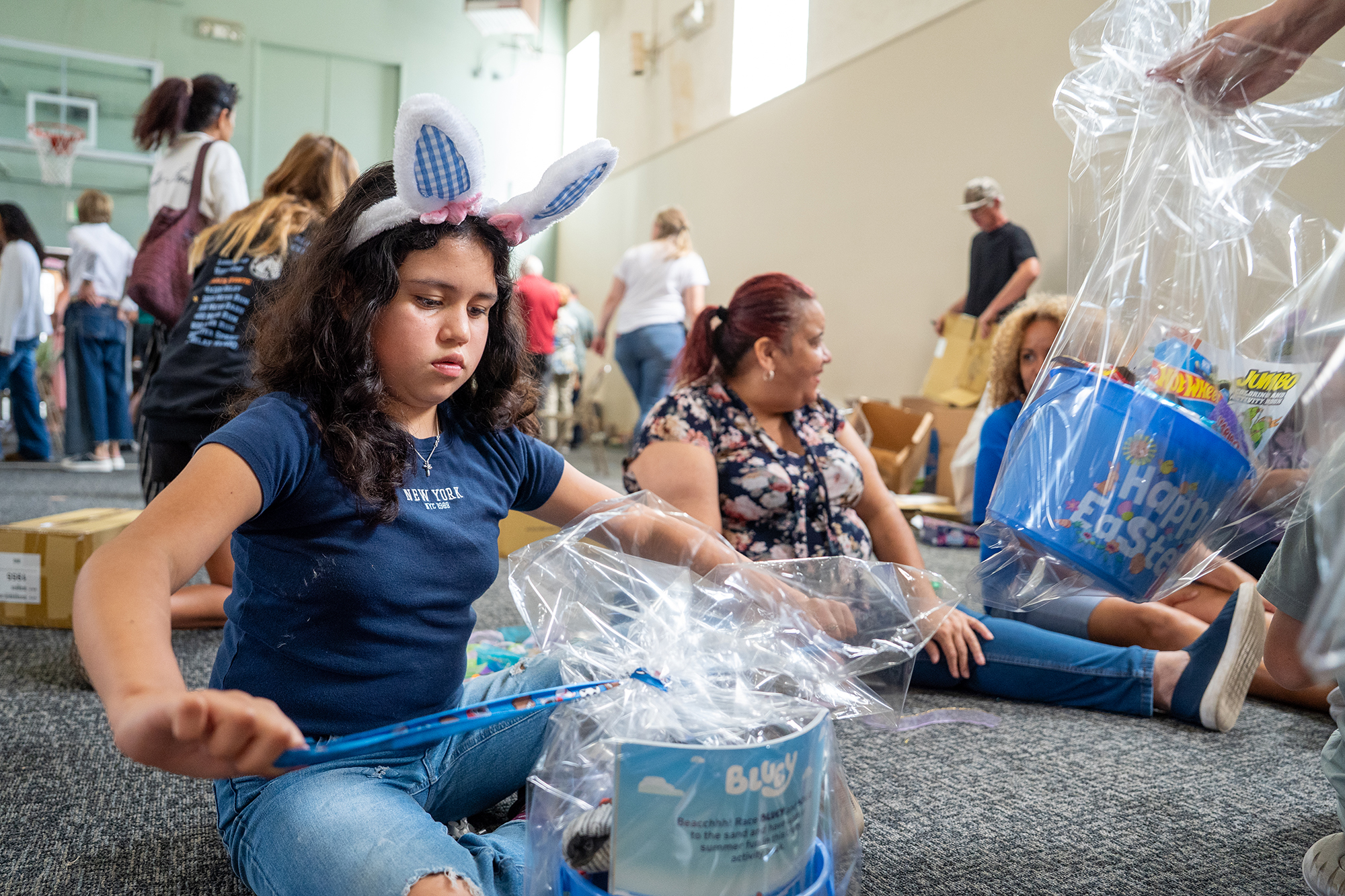 A young volunteer ties cellophane around a gift basket as...