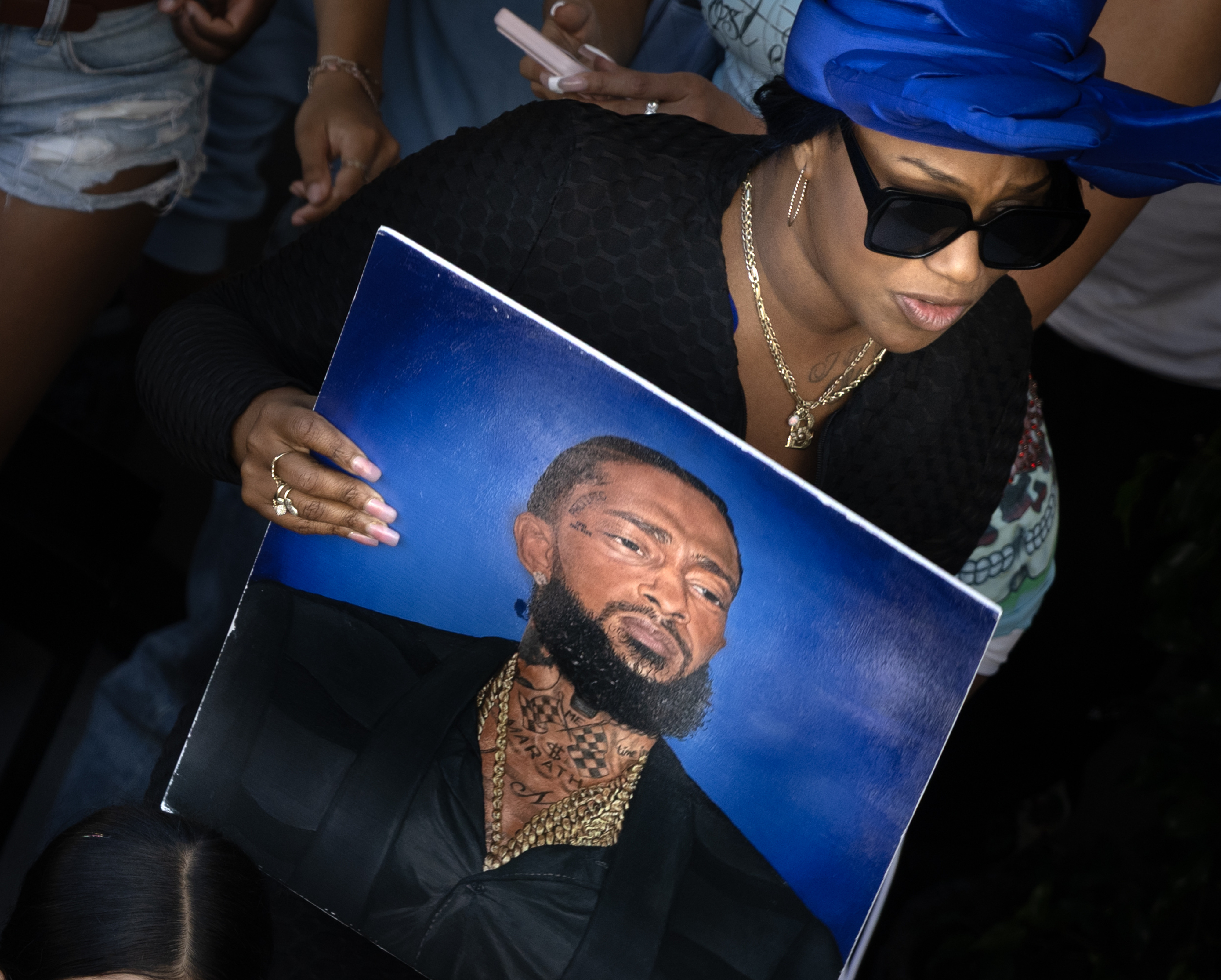 Jazz Ledbetter carries a photo of the late rapper Nipsey...