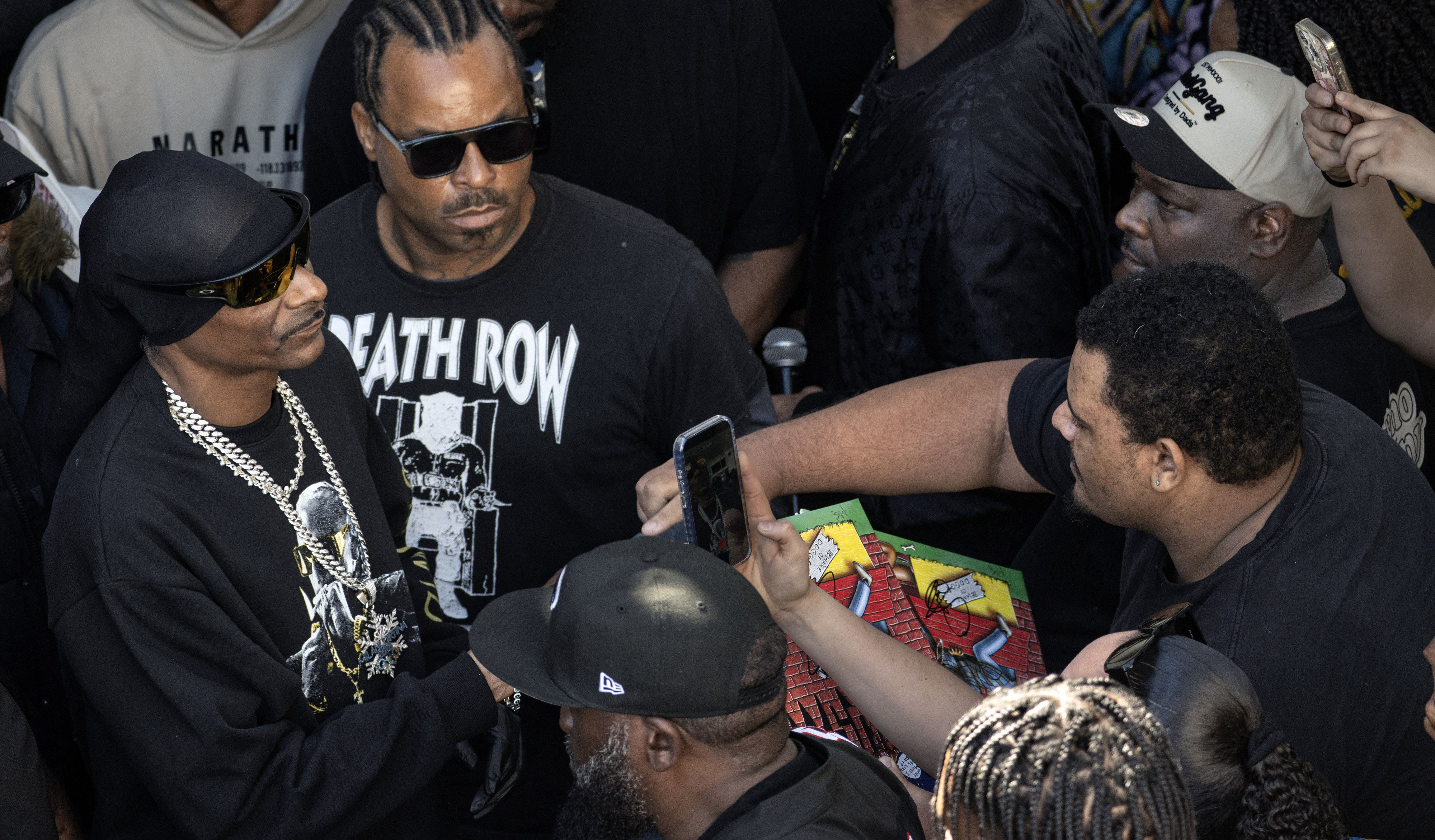 Rapper Snoop Dogg, far left, takes time to sign an...