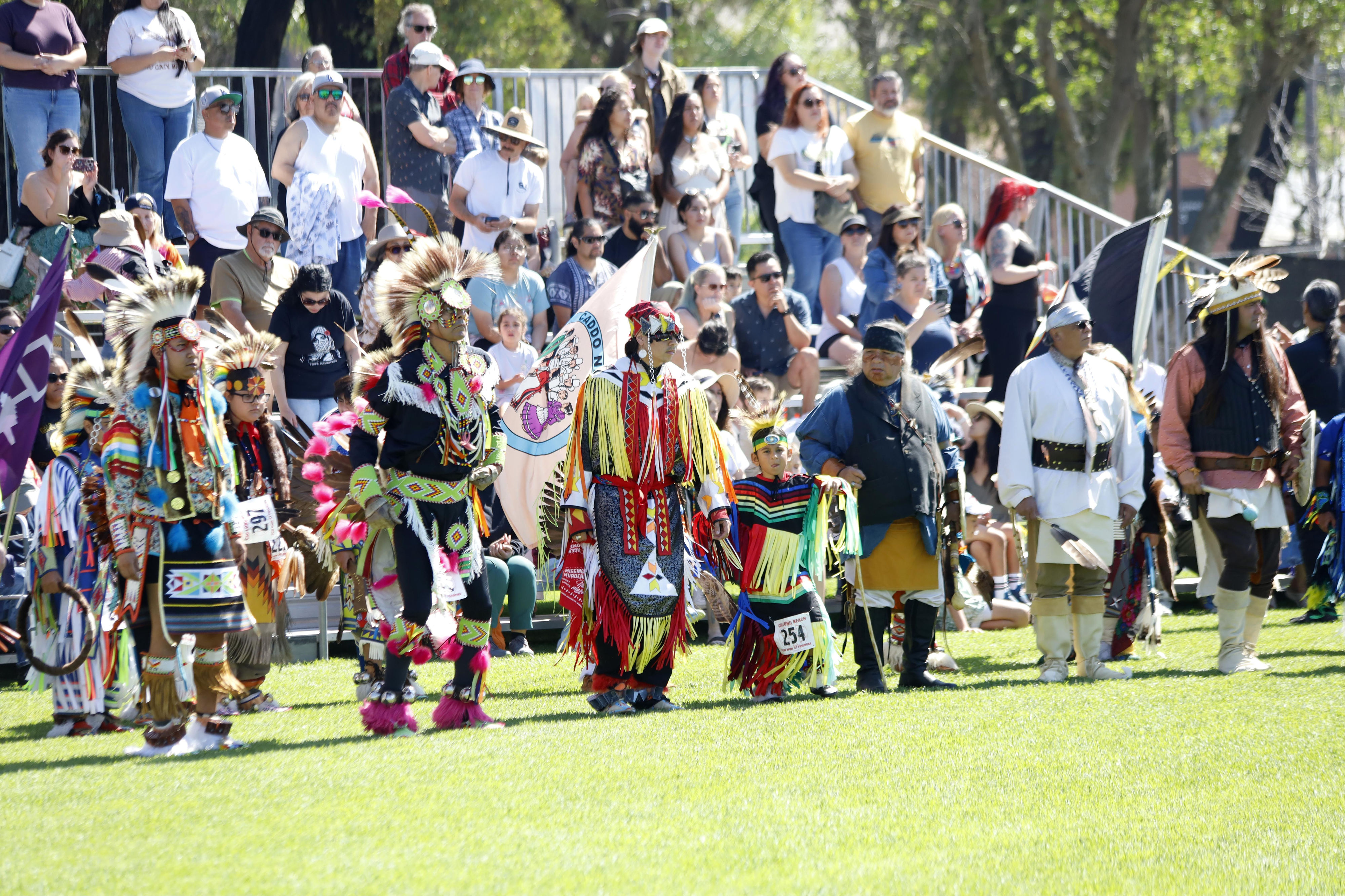 Dancers line up in front of the bleachers which are...