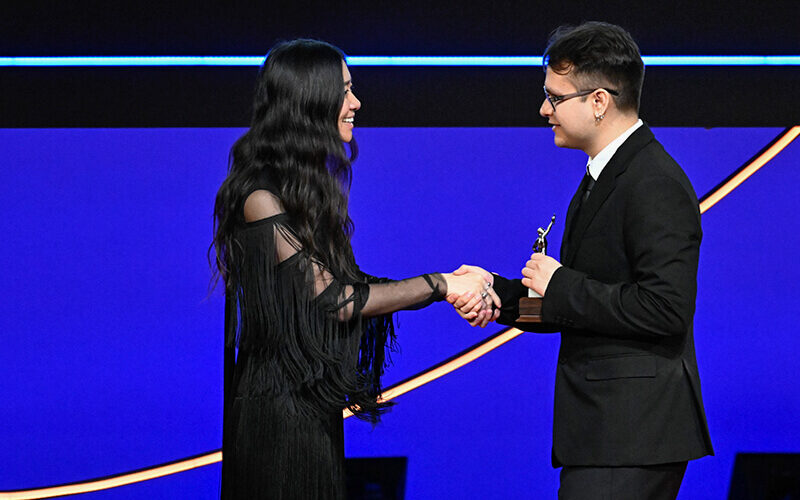 CSUF student Luis Barragan accepts the Anne V. Coates Award for Student Editing and shakes hands with Chloe Zhao, director and filmmaker
