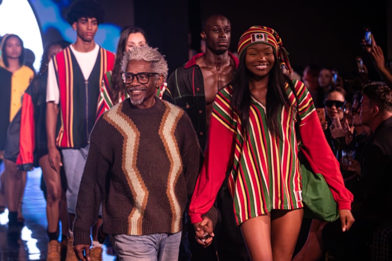 Photo of models walking with their designer.