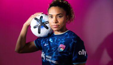 Catarina Macario wears a blue San Diego Wave jersey and holds an NWSL soccer ball.