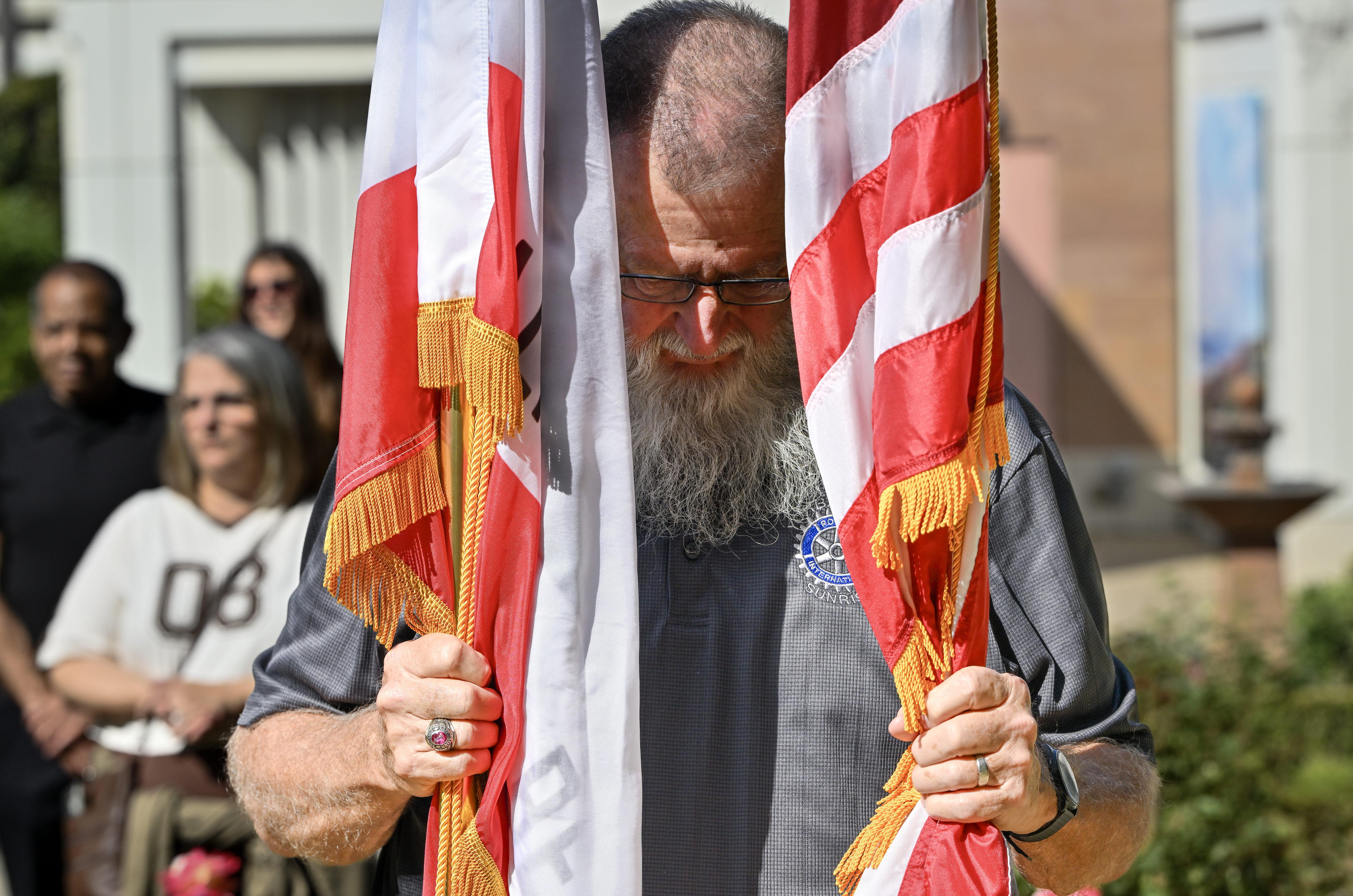 Mike Shanahan holds on to two flags during a wreath...