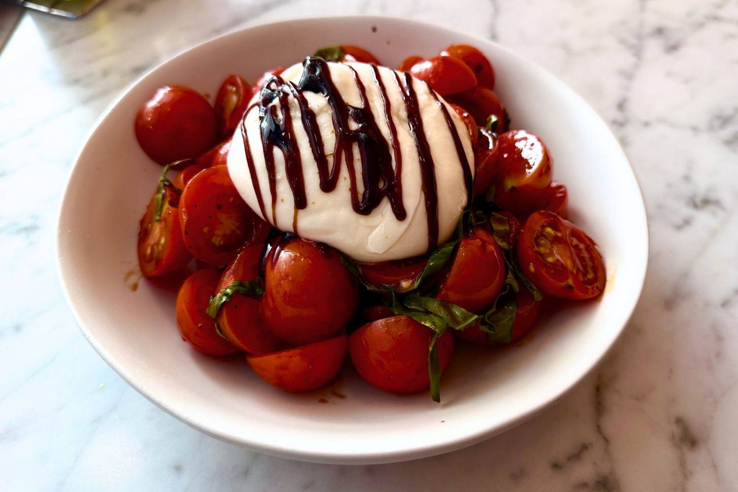 A burrata and tomato salad from Pinwheel Pasta, located in...