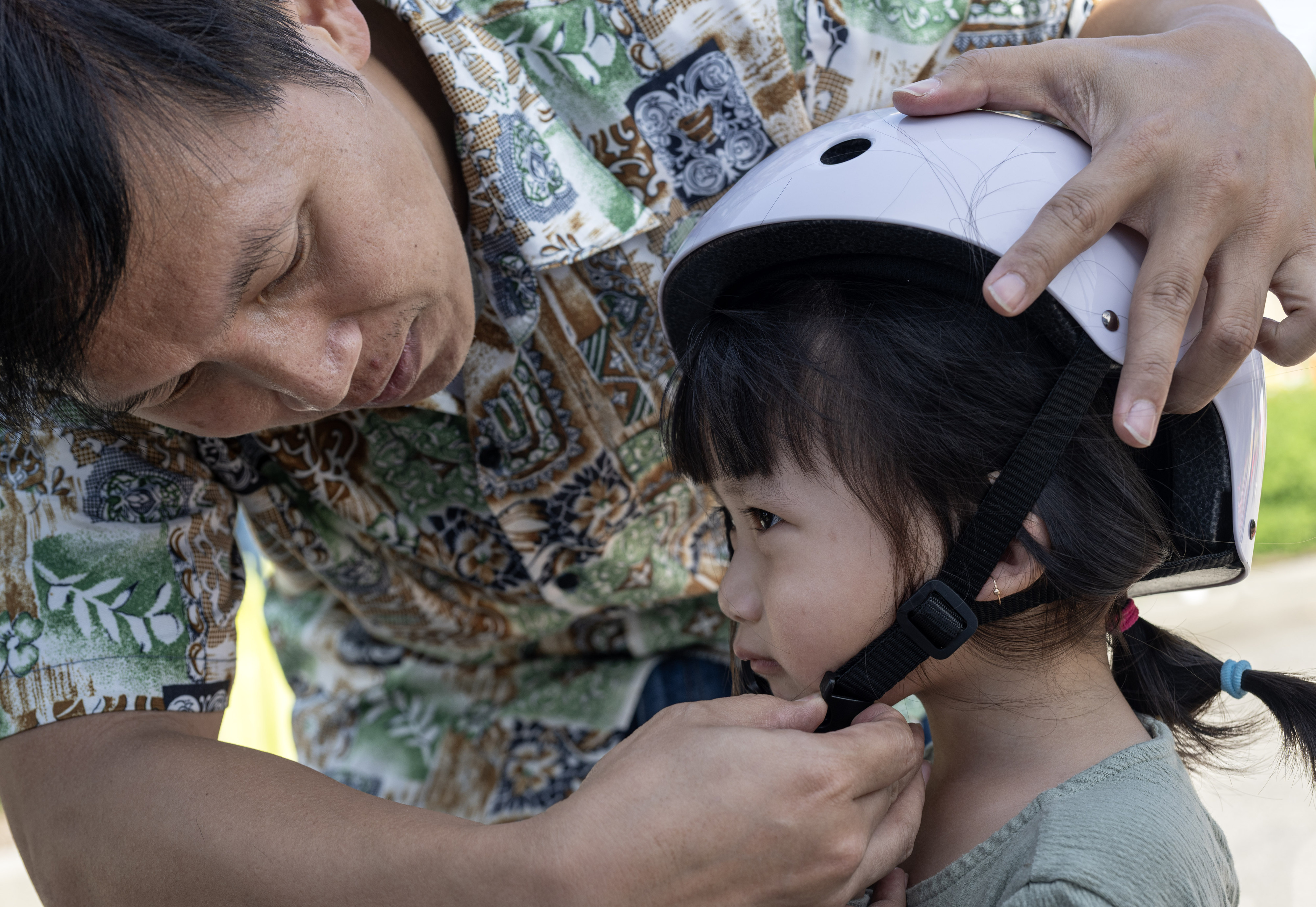 Henry Vu removes his 3-year-old daughter Evelynâs helmet after she...