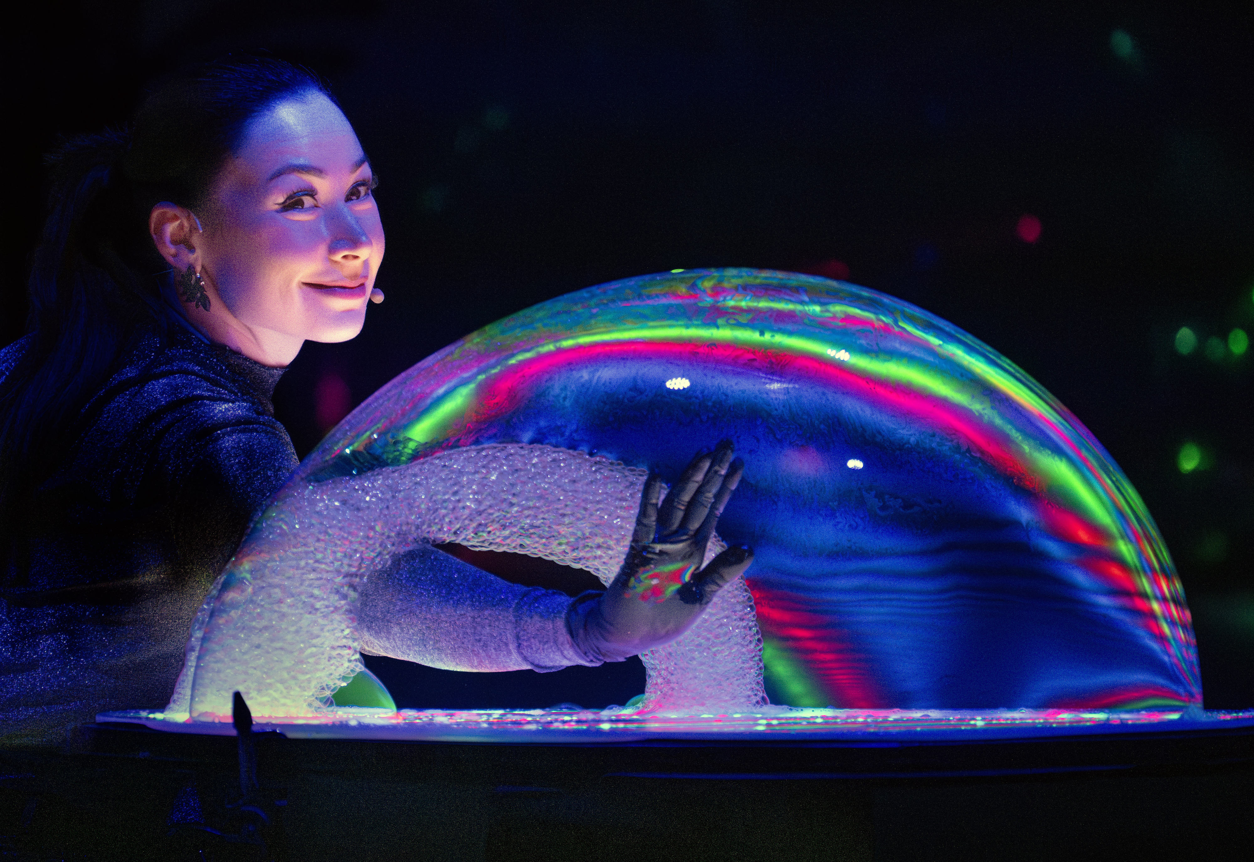 Bubble artist Melody Yang reaches inside a colorful bubble creation...