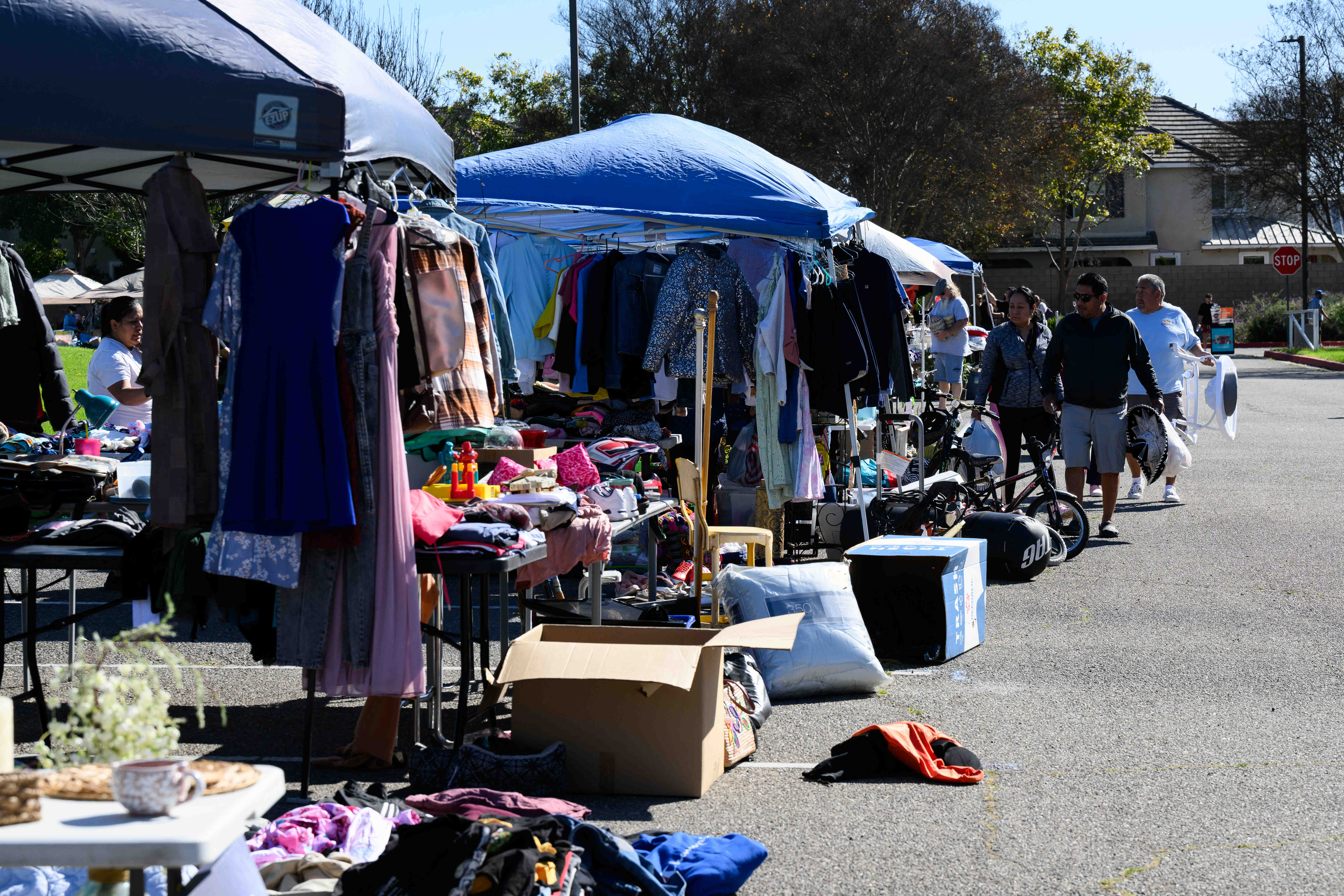 Shoppers walk along display stalls during a community yard sale...