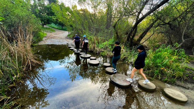 Hikers use the stepping stones to cross Santiago Creek just after sunrise on Saturday, February 28, 2026, as they make their way to the trails for a morning hike in Santiago Oaks Regional Park in Orange. (Photo by Mark Rightmire, For the Orange County Register/SCNG)