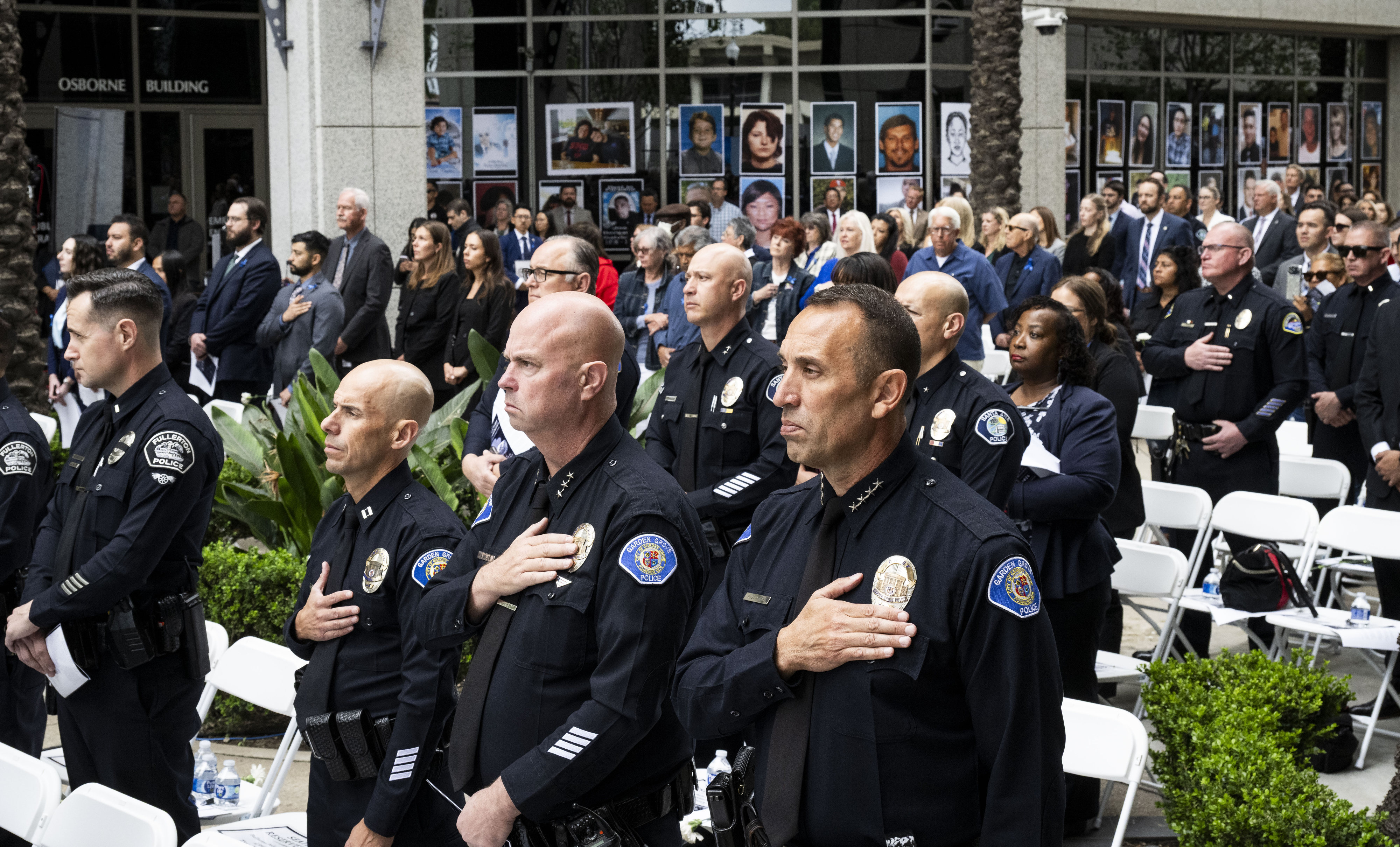 People listen as the National Anthem is played during the...