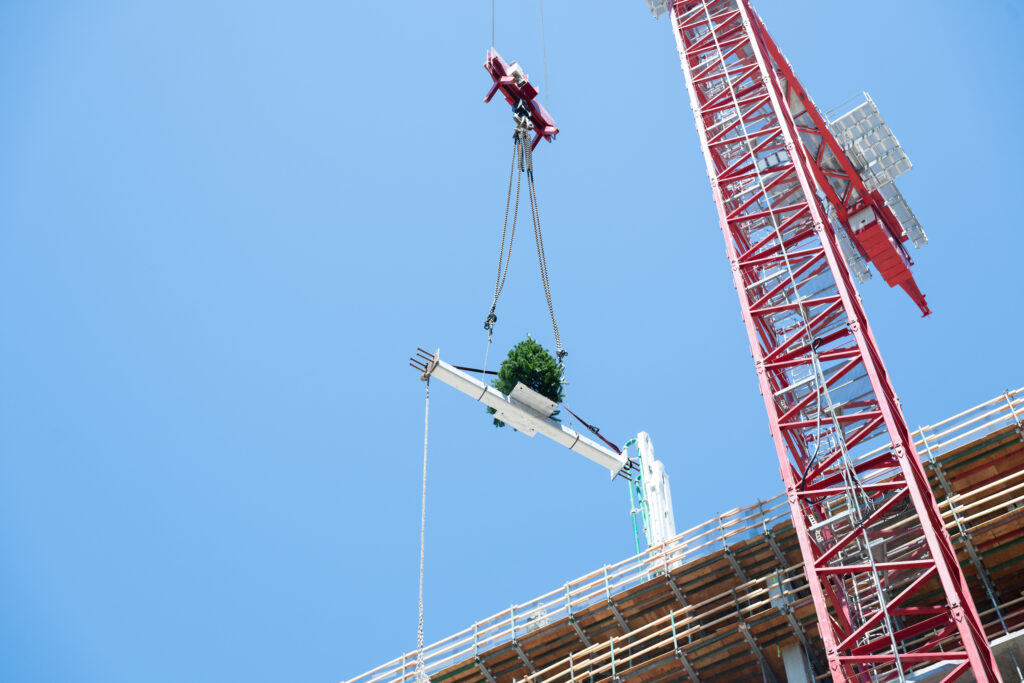 construction crews raise a beam with a crane high above the ground during the topping-out event at the people's park construction site, a significant milestone in the project's construction.