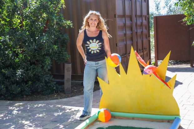 Chelsea Haukom, owner of Spray of Sunshine Spray Tans in Ramona, stands with her miniature golf course that brought a beachy and summer feel to the event. (Stephanie Ogilvie)