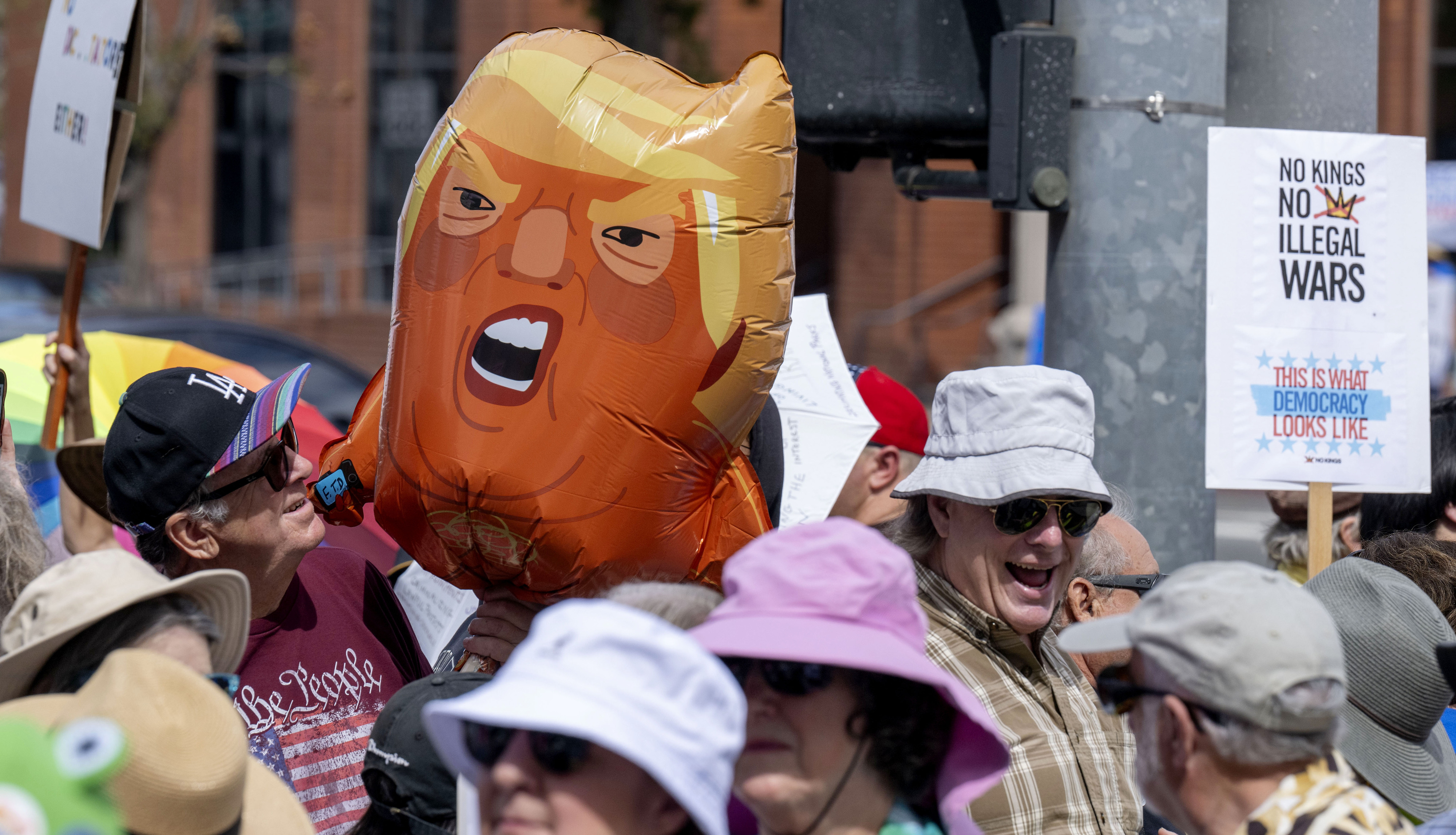 “No Kings” demonstrators with balloons and signs peacefully protest at...