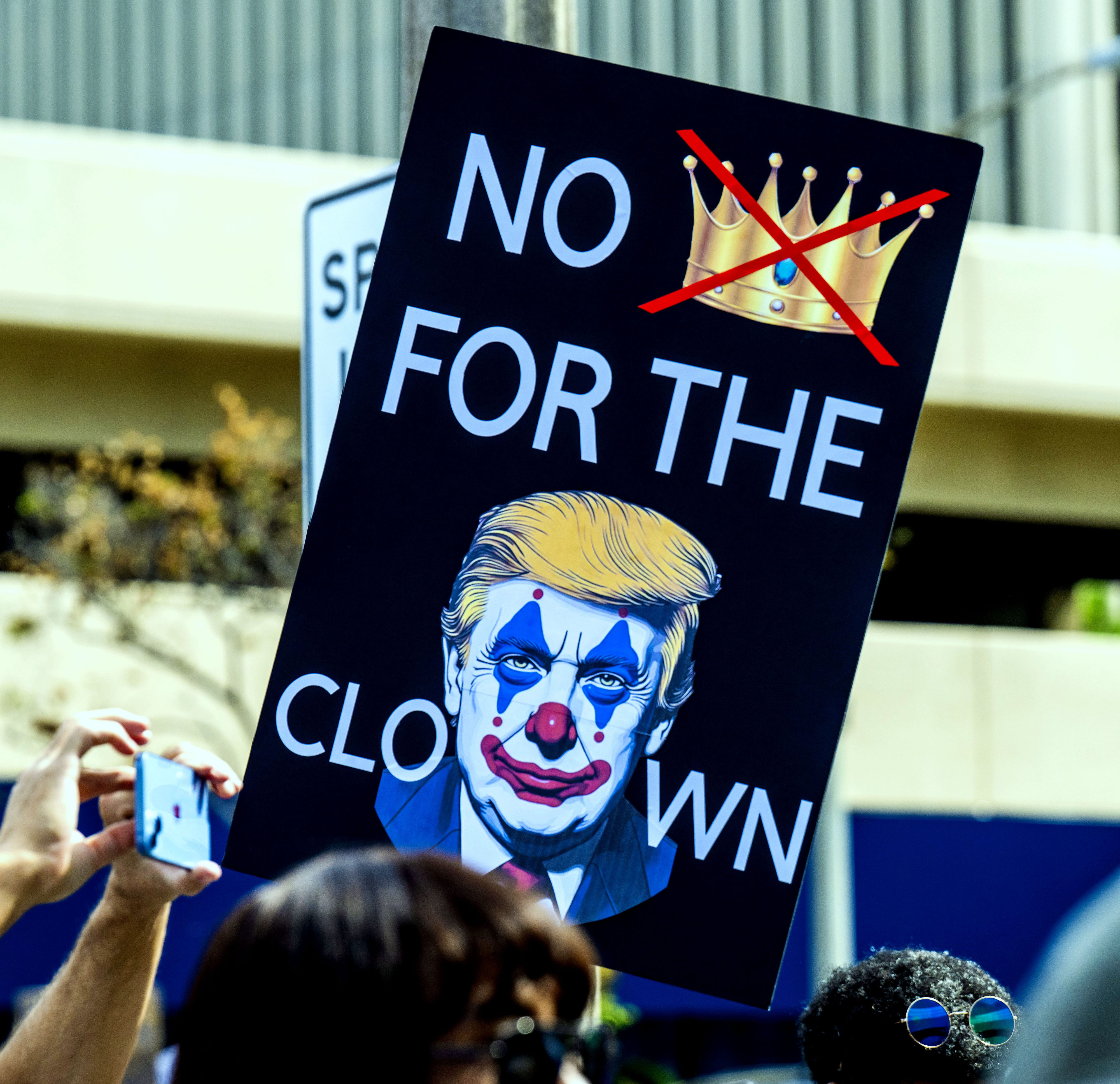 Hundreds of “No Kings” protesters carried signs at the intersection...