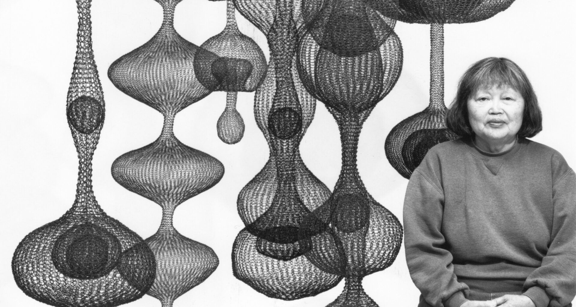 woman next to globular mesh hanging sculptures