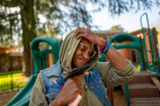 Tanika Williams, 40, shows signs of frustration as she calls the city’s 211 emergency shelter line for the second time as she stands in James Marshall Park in Sacramento on March 9. She, her husband and their daughter are homeless. A 211 operator said all shelters were full.