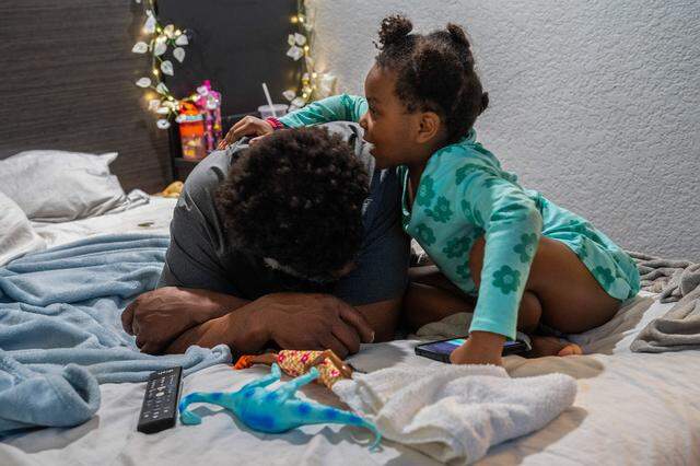 Makhìla Williams, 4, who has sickle cell disease, hugs her father Michael Williams, who has chronic obstructive pulmonary disease, in a hotel room in Sacramento on March 3. Because they of their health conditions, they are afraid to enter congregate shelters — where illness can spread rapidly.