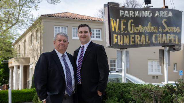 Patrick Gormley and Patrick Gormley Jr. stand next to the neon sign in the parking lot of W.F. Gormley & Sons in Sacramento on March 13. The funeral business, which the Gormley family has operated for 129 years, is moving from midtown to Land Park.