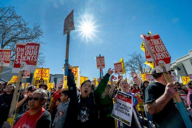 Sang Nguyen, center, an eighth-grade math teacher at Rio Tierra School, holds a sign while joining hundreds of striking teachers and supporters at the Twin Rivers district office at McClellan Park on Thursday.