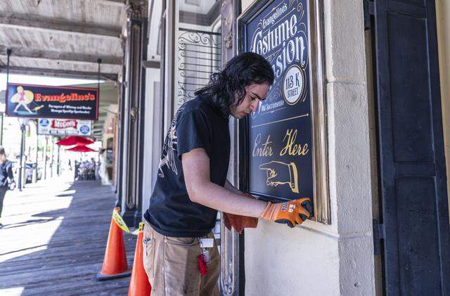 Erik Garcia, an employee with Evangeline’s Costume Mansion, cleans a marquee Tuesday as the store annouces its reopening after a fire last year. A grand opening will be held on June 27 and 28.  