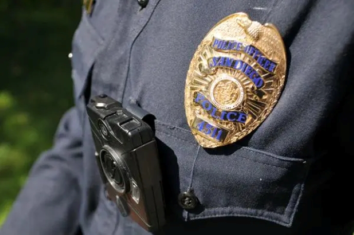 Close-up of a police uniform with a gold badge and body camera.