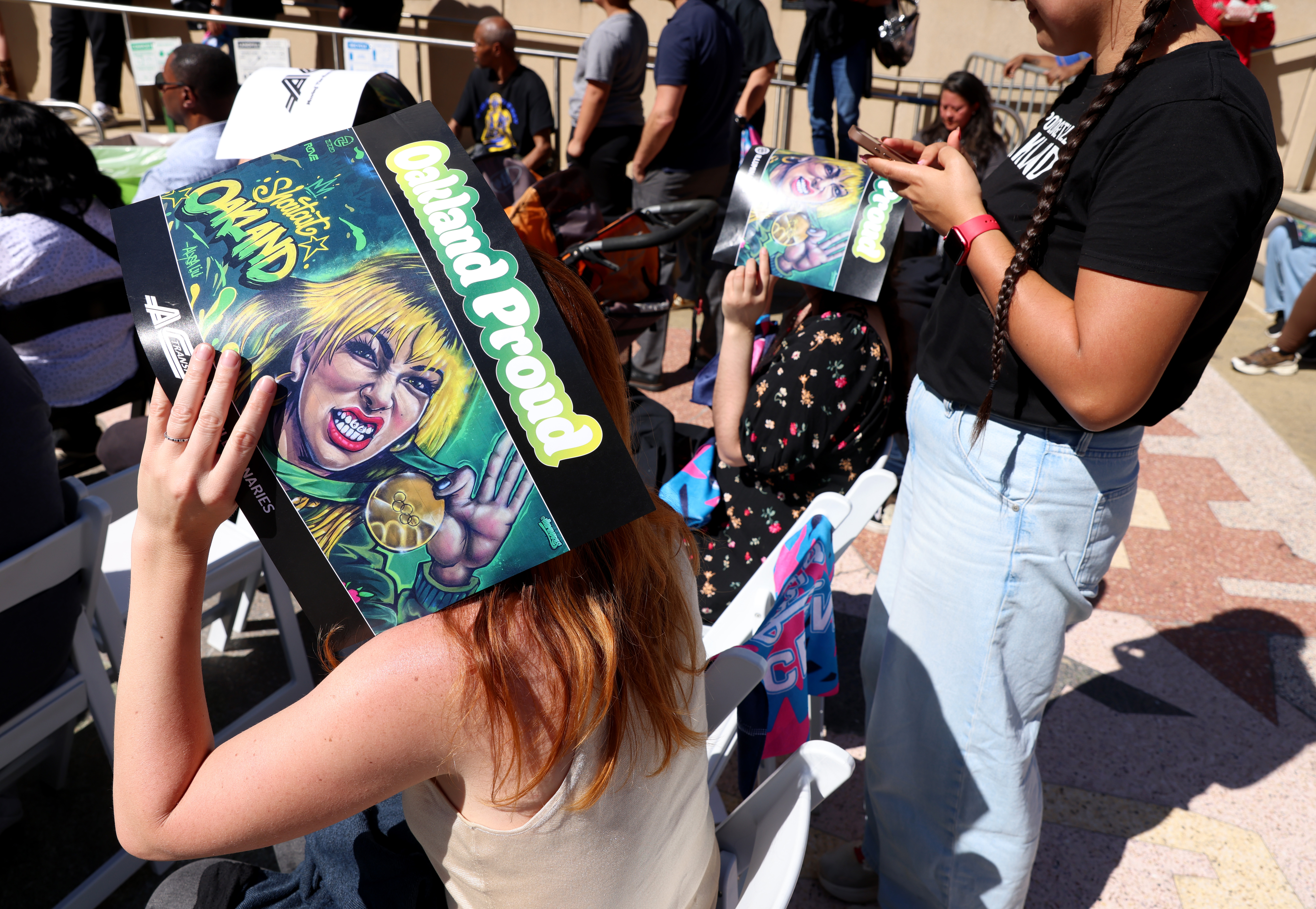 People shield themselves from the sun with posters during a...