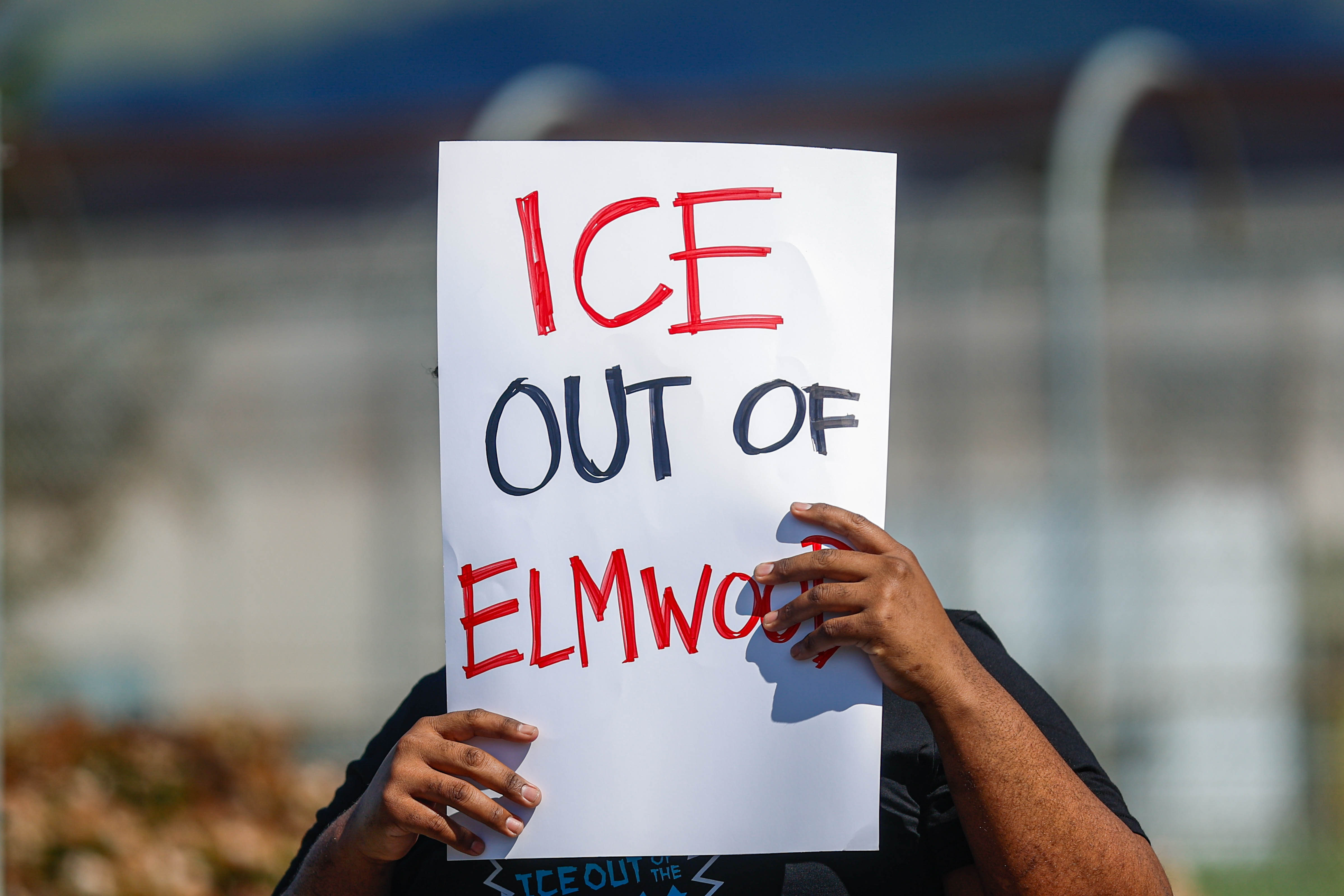 A person holds a sign while protesting ICE at Elmwood...