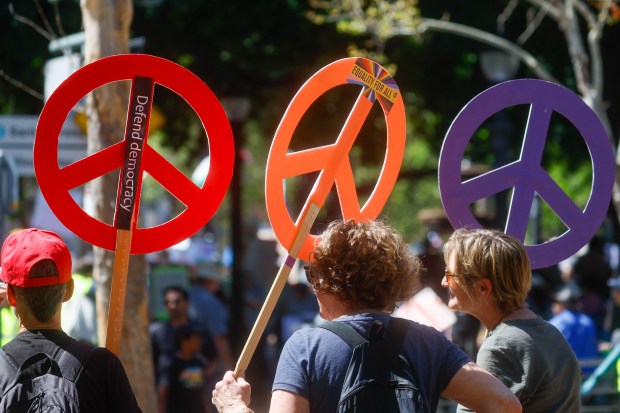 People carry peace signs during a No Kings protest at St. James Park in downtown San Jose, Calif., on Saturday, March 28, 2026. (Shae Hammond/Bay Area News Group)