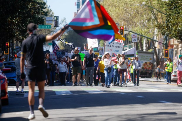 People carry signs and walk down East Santa Clara Street during a No Kings protest in downtown San Jose, Calif., on Saturday, March 28, 2026. (Shae Hammond/Bay Area News Group)