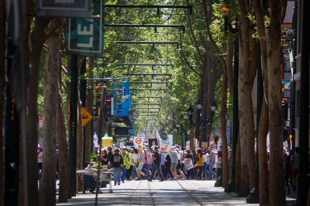 People carry signs and walk down East Santa Clara Street during a No Kings protest in downtown San Jose, Calif., on Saturday, March 28, 2026. (Shae Hammond/Bay Area News Group)