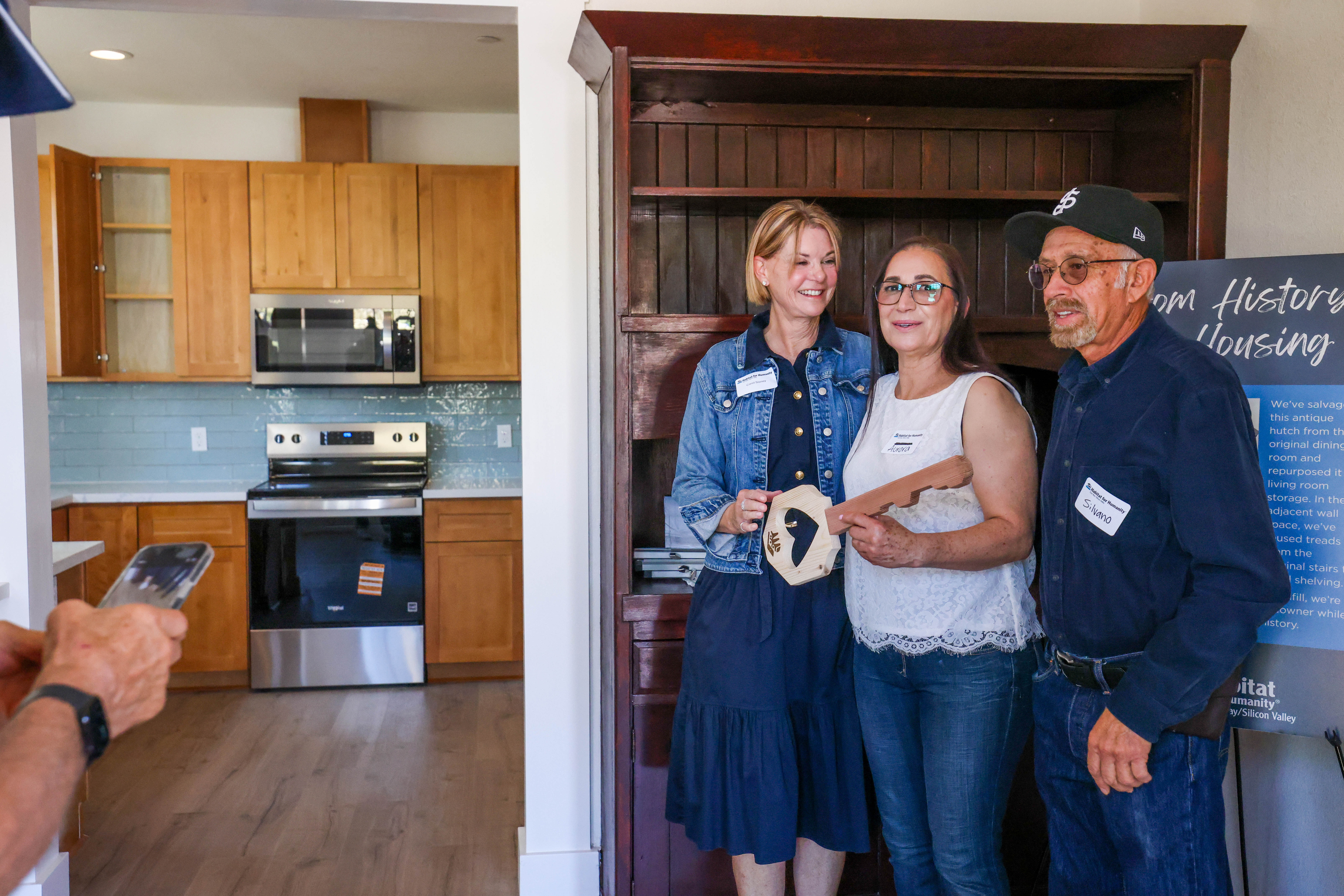Former homeowner Carol Sisney, left, stands next to new homeowners...