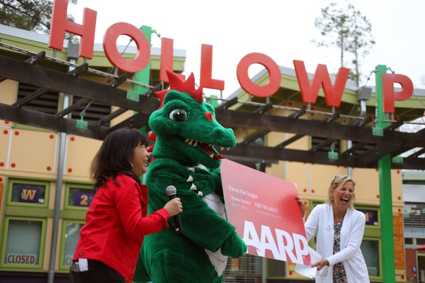 Sophie Horiuchi-Forrester, left, of the American Association of Retired Persons and Happy Hollow Foundation member Lissa Kreisler, right, present an AARP card to park mascot Danny the Dragon on Thursday, May 25, 2023, at Happy Hollow Park and Zoo in San Jose, Calif. The event celebrated the 62 anniversary of the park and took place on the first Senior Safari day of the season. (Aric Crabb/Bay Area News Group)