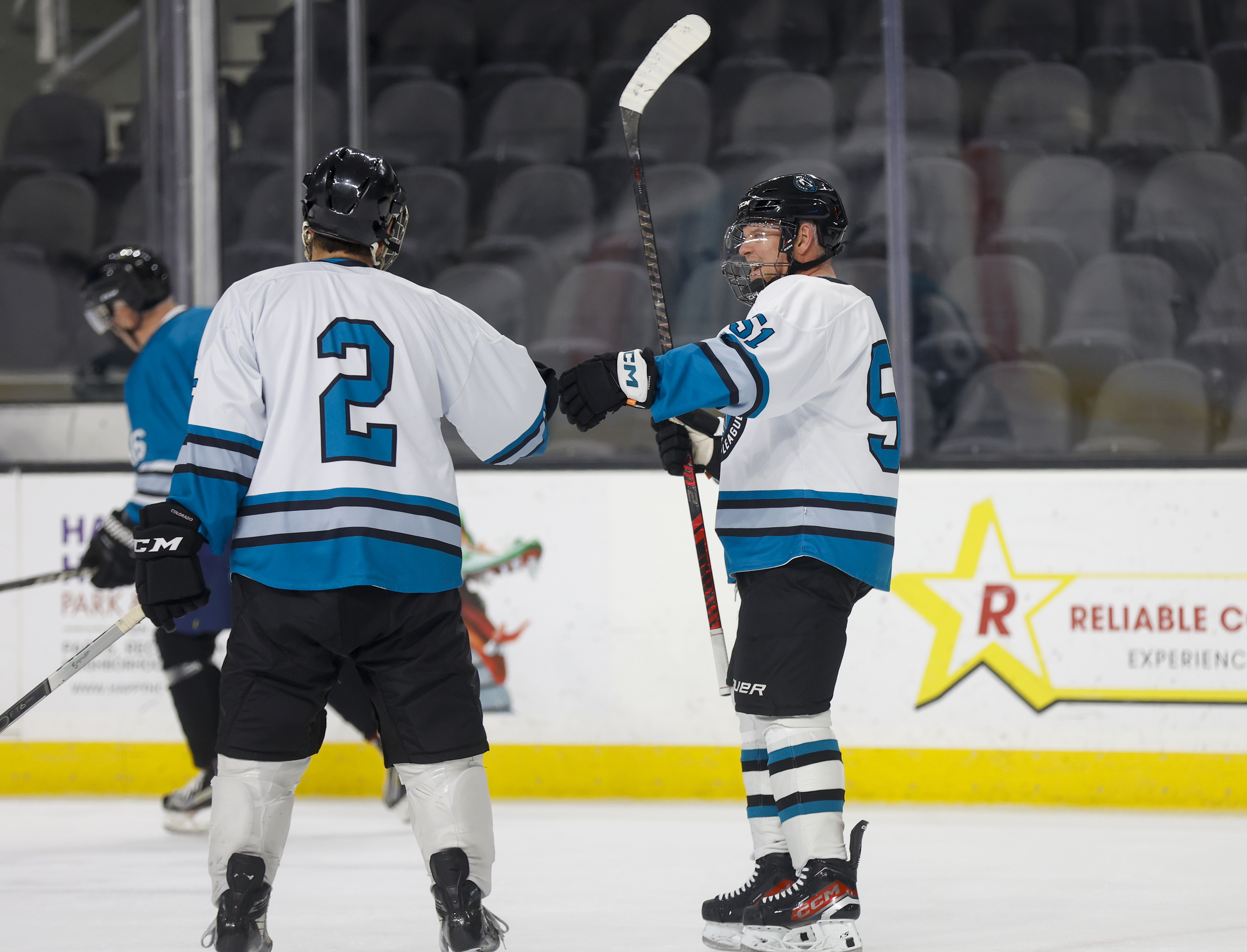 Dean Tait (51), right, adult hockey manager, celebrates a teammates...