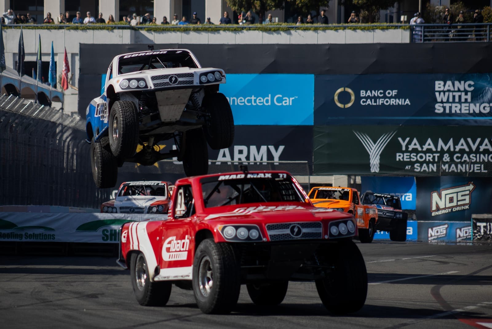 A white and blue truck flies into the air during a race.