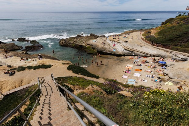 Beachgoers relax and take a dip in the water at Santa Cruz Cliffs in Ocean Beach on Friday, March 13, 2026. (Kristian Carreon / The San Diego Union-Tribune)