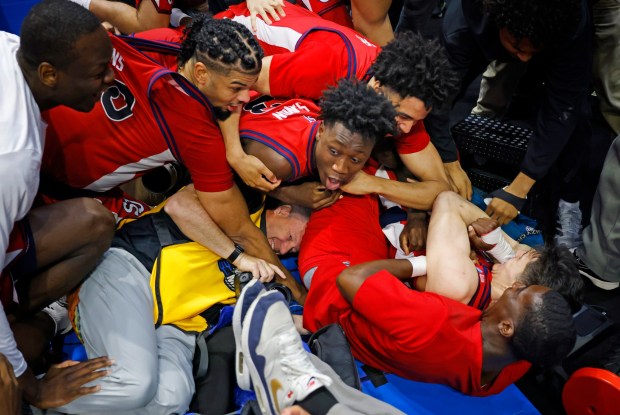 NCAA photographer Jamie Schwaberow finds himself at the bottom of the celebration when St. John's guard Dylan Darling was mobbed by teammates after game-winning shot.(K.C. Alfred / The San Diego Union-Tribune)