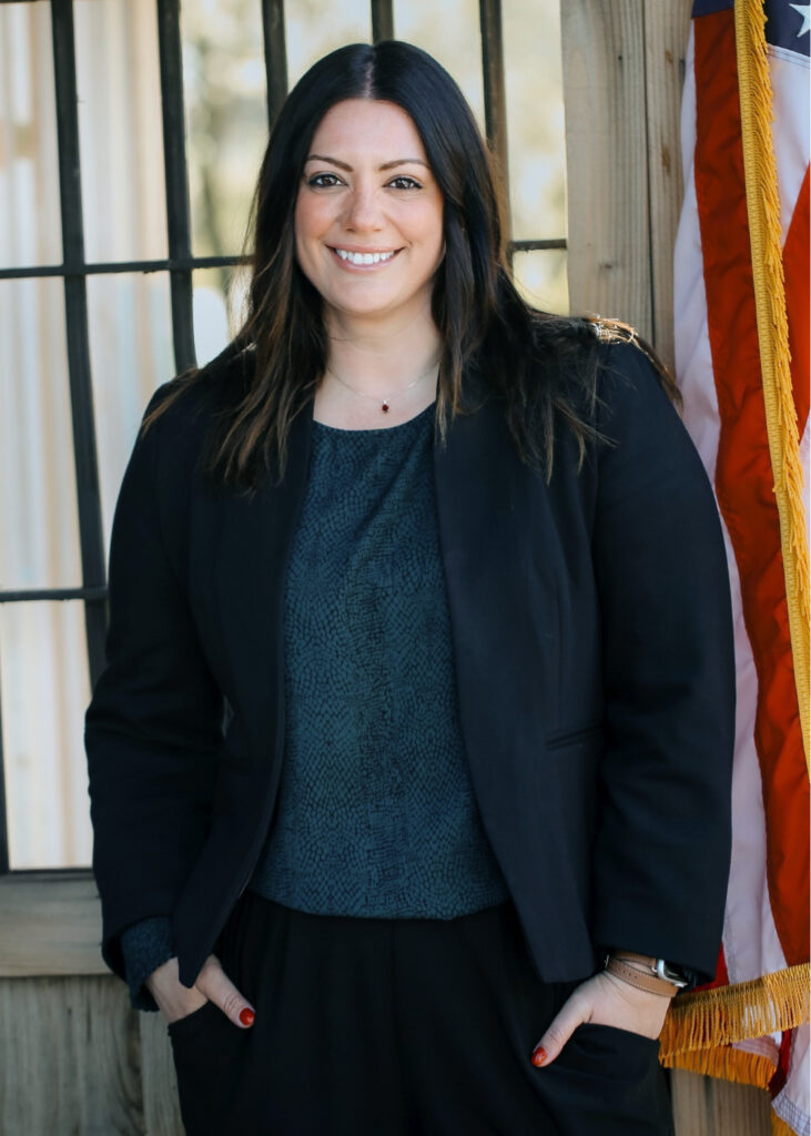 informal portrait of Sarah Edwards, standing before a paned glass window and with an American flag at the right margin